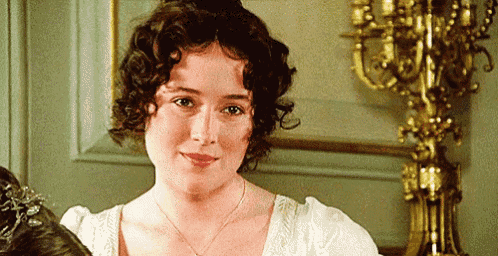 a woman with curly hair is standing in front of a candle holder .