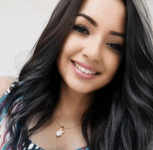 a woman with long black hair is smiling for the camera