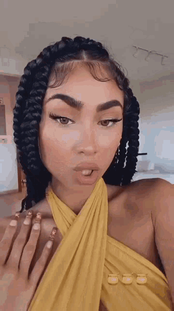 the woman is wearing a yellow dress and has braids in her hair .
