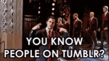 a man in a suit and tie is standing in front of a group of men and says you know people on tumblr .