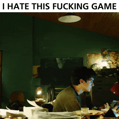 a man sits at a table with the words i hate this fucking game on the bottom