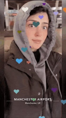 a woman wearing a hooded jacket is at manchester airport in the uk