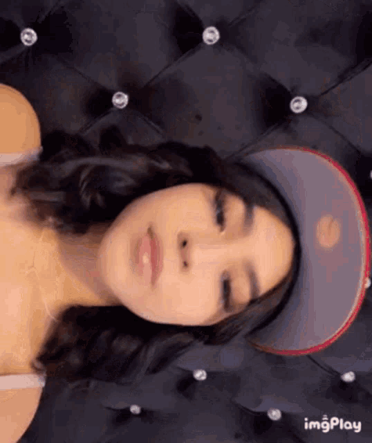a woman is wearing a baseball cap and laying on a bed .