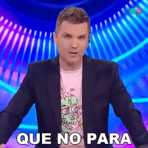 a man in a suit stands in front of a microphone and says que no para