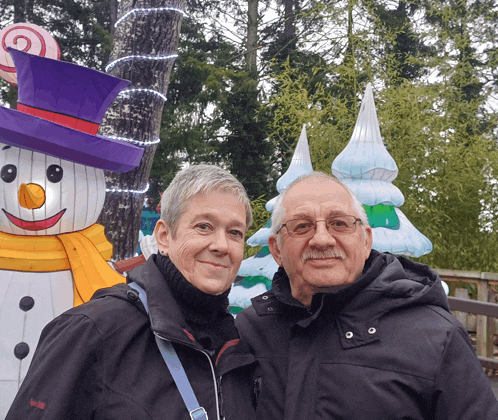 a man and woman pose in front of a snowman