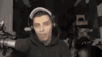 a man wearing headphones is standing in front of a microphone in a dark room .