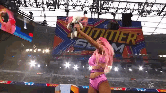 a woman with pink hair is holding a trophy in a ring .