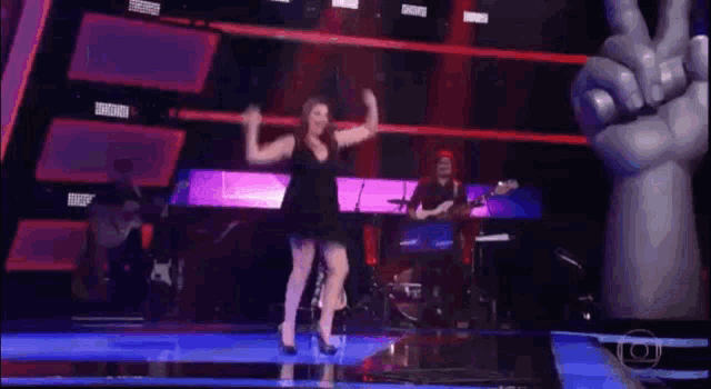 a woman in a black dress is dancing on a stage .