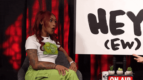 a woman sitting in front of a sign that says hey ew