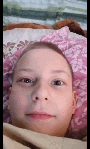a young boy is laying on a bed with a floral pillow
