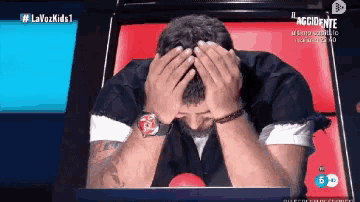 a man is covering his face with his hands on a tv screen