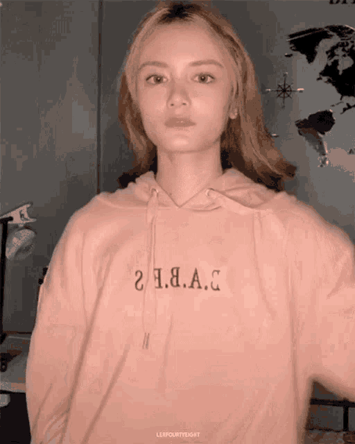 a woman wearing a pink hoodie that says 2 a.b.a.c