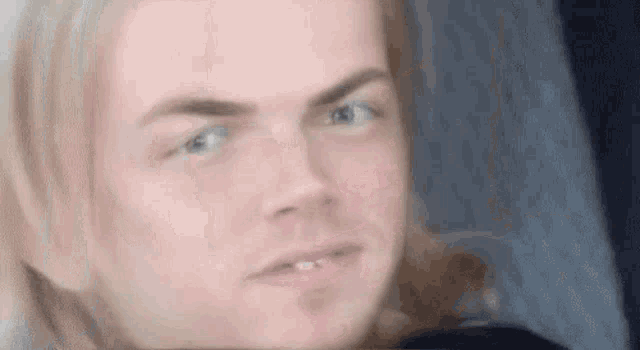 a man with long hair is making a funny face .