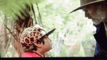 a man and a child are standing next to each other in the woods .