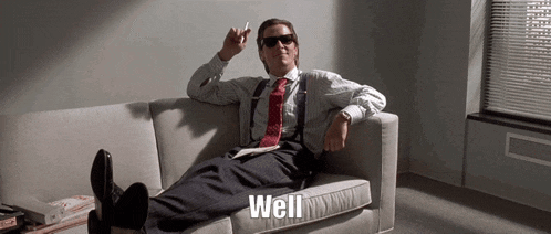 a man in a suit and tie is sitting on a couch with his feet up and the words well below him