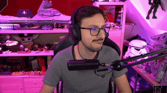 a man wearing headphones and a gray shirt that says racing