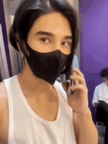 a man wearing a mask and talking on a cell phone .