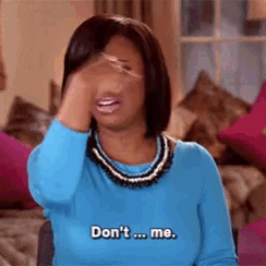 a woman in a blue sweater is covering her face with her hand and saying " don 't me "