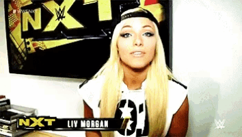 a woman with blonde hair is standing in front of a sign that says nxt liv morgan