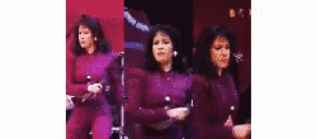 a woman in a purple jumpsuit is dancing on a stage .