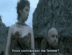 a man and a woman are standing next to each other . the woman is naked and the man is bald .