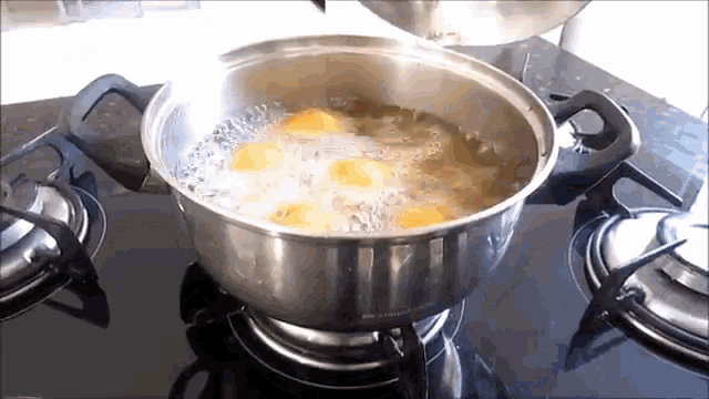 eggs are being cooked in a pot of water on a stove