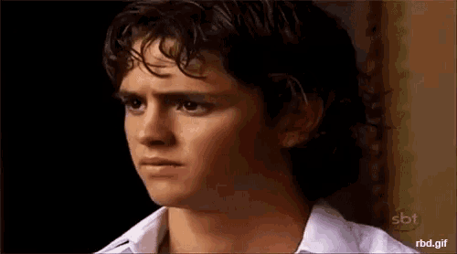 a close up of a young man 's face with a white shirt on .