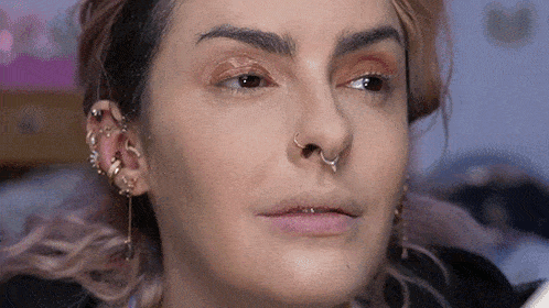 a close up of a woman 's face with a nose ring and piercings .