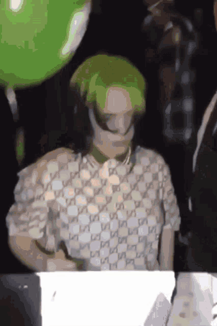 a woman wearing a green hat and a gucci shirt signs a piece of paper