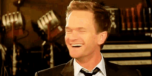 a man in a suit and tie is laughing in front of a microphone .