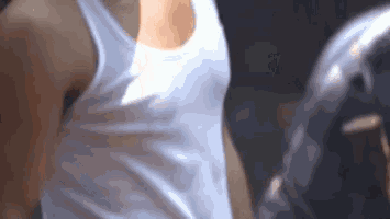 a man wearing a white tank top is standing in front of a mirror .