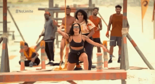 a group of people are standing around a woman sitting on a wooden beam .