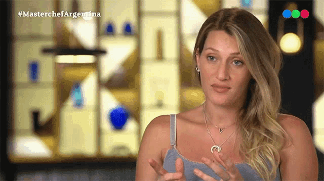 a woman in a gray tank top is talking on a television show called masterchef argentina