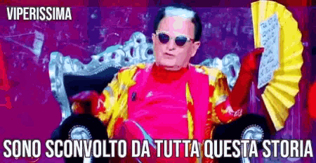 a man holding a fan with the words sono sconvolto da tutta questa storia underneath him