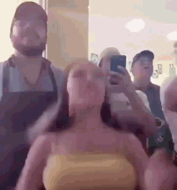 a woman in a yellow tank top is taking a picture of herself with a cell phone .