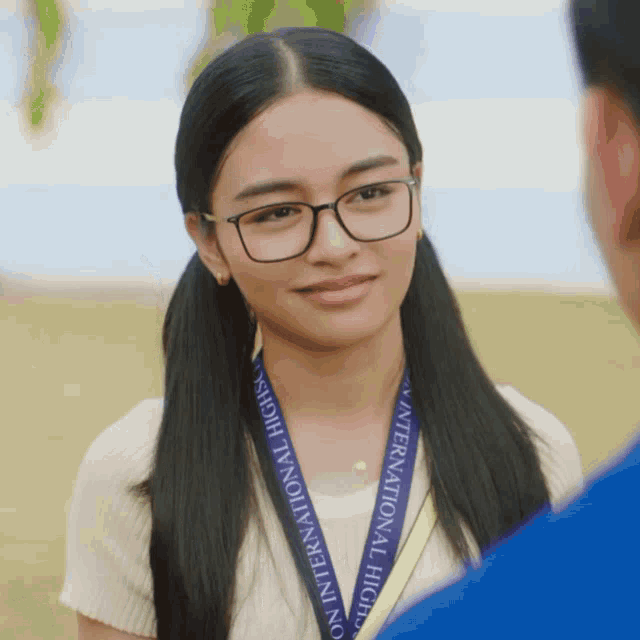 a girl wearing glasses and a lanyard that says international high