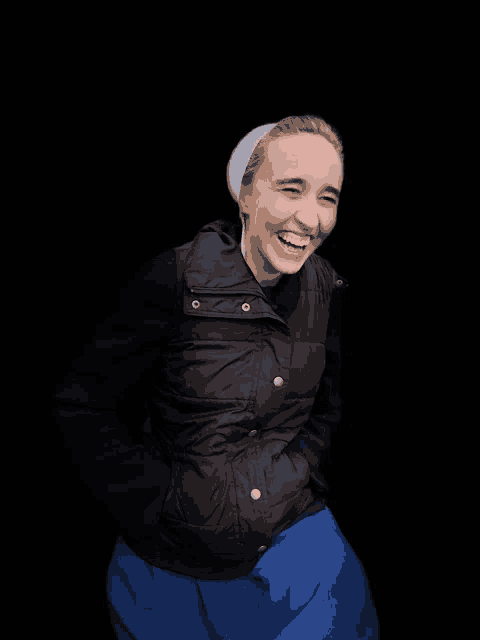 a woman wearing a black vest and a blue skirt laughs