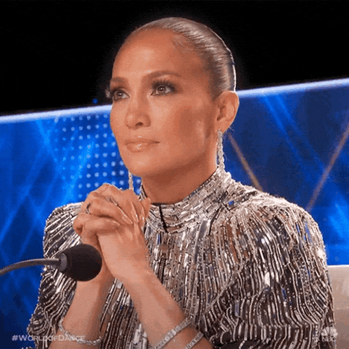 a woman in a sequined dress is sitting in front of a microphone