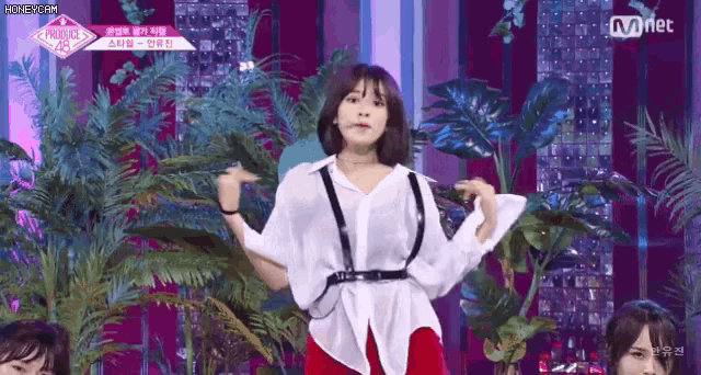 a woman in a white shirt and red pants is dancing on a stage