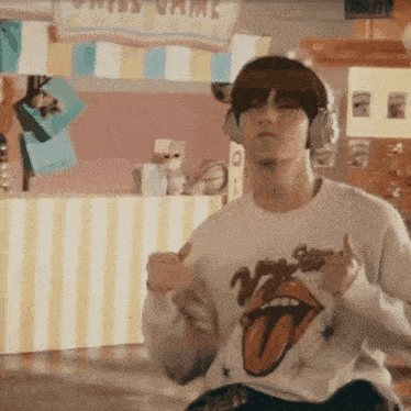 a man wearing headphones and a rolling stones t-shirt is dancing in a room .