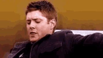a man is sitting on a bench with his arms outstretched and making a funny face .