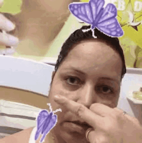 a woman is cleaning her nose with a butterfly on her head .