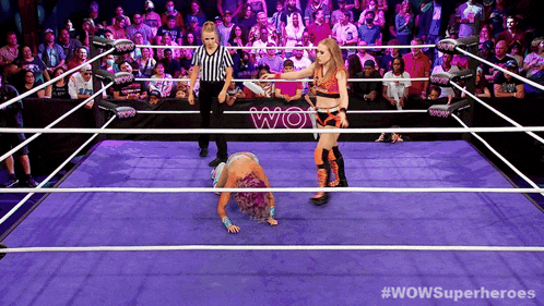 two women wrestling in a wow wrestling ring with a crowd watching