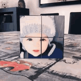 a cube with a picture of a child 's face on it is on a table .