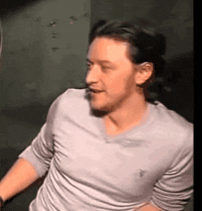 a man wearing a white shirt is standing in a dark room .