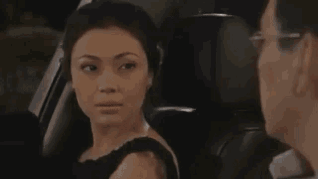 a woman is sitting in a car with a man and talking to him .