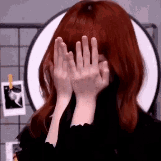 the woman is covering her face with her hands .