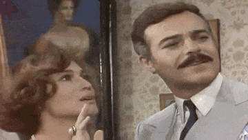 a man and a woman are standing next to each other in front of a painting .