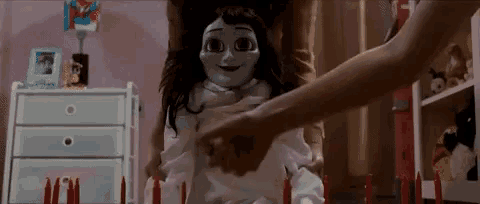 a person is holding the hand of a doll in a room .