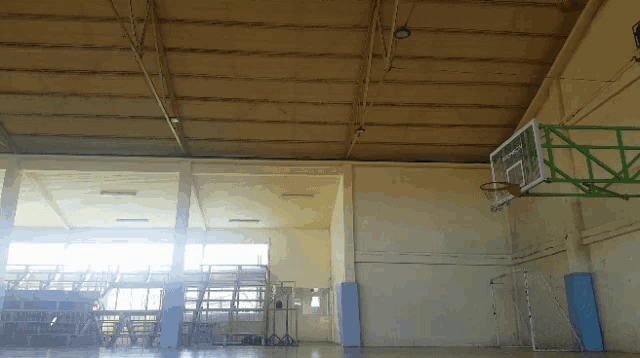 an indoor basketball court with a green hoop and a sign that says " basketball "